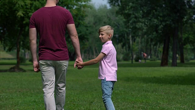 爸爸和男孩手牵着手，离开，养育和友谊，幸福的家庭视频下载