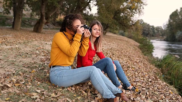 两个女性朋友坐在河边，女摄影师和她的模特。视频素材