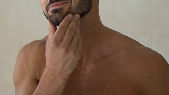一名男子在浴室的镜子前骄傲地摸着自己的胡子视频下载