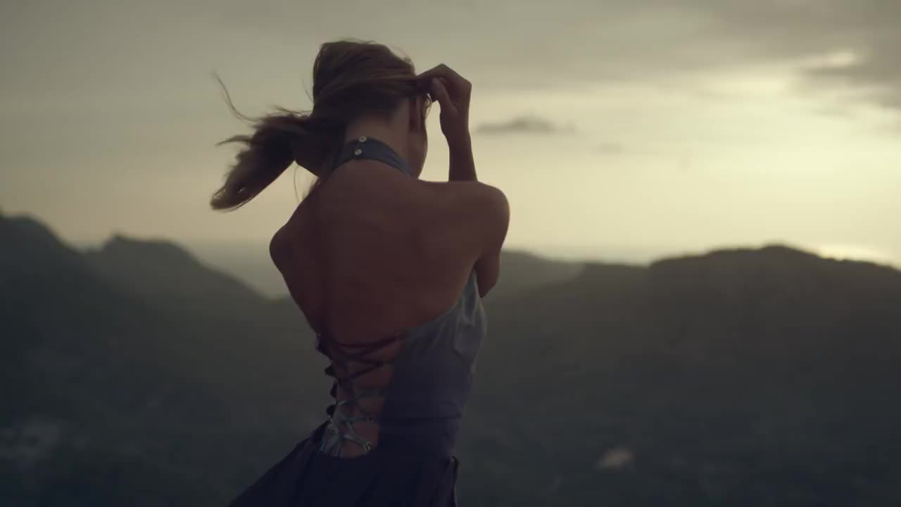 浪漫的女孩穿着长裙享受着风。从悬崖上看风景视频素材