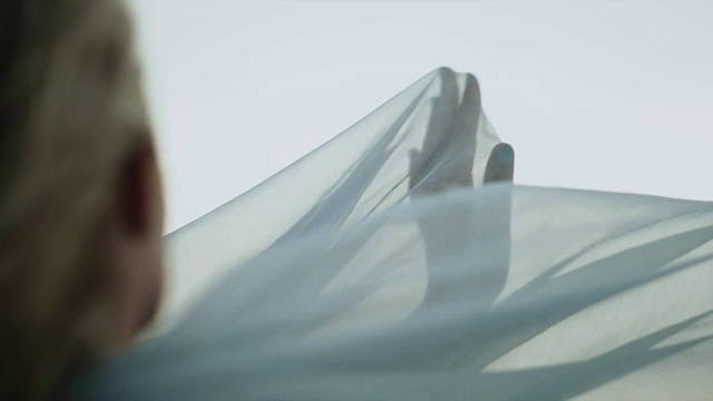浪漫的女孩穿着长裙享受着风。藏在透明的纺织品里视频素材