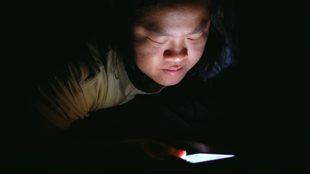 亚洲女性在床上使用智能手机视频下载