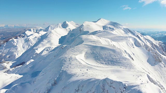 航拍图:在一个壮观的冬日里，沿着积雪覆盖的山脊飞行。视频素材
