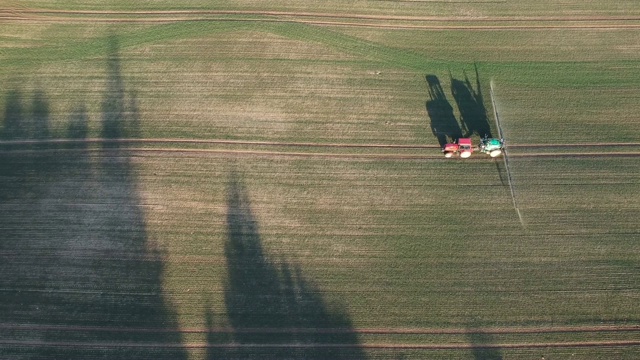 农用拖拉机在傍晚喷洒秋季作物田，鸟瞰图视频素材
