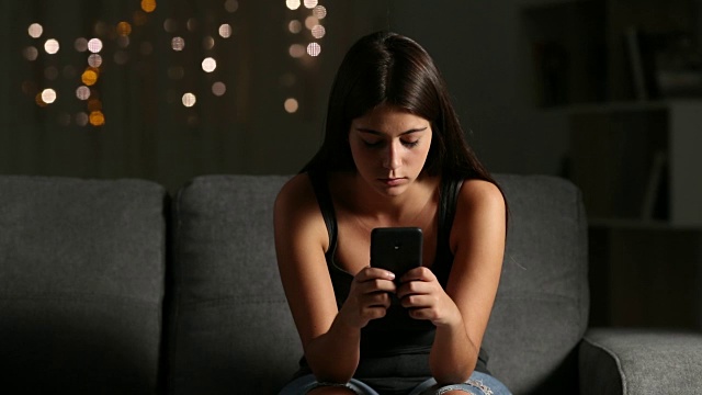 可悲的女孩在看网络欺凌的手机短信视频素材