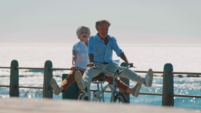 一对老年夫妇在人行道上骑双人自行车视频素材