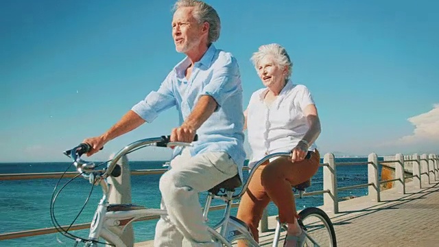 一对老年夫妇在阳光明媚的日子里享受双人自行车视频素材