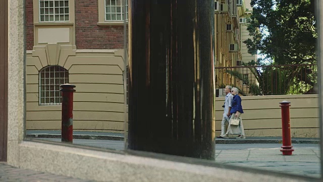 一对老年夫妇走在城市的人行道上视频素材