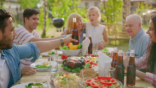 大型家庭花园聚会庆祝，聚在桌子上，吃，开玩笑，玩。滑球越过桌子。视频素材