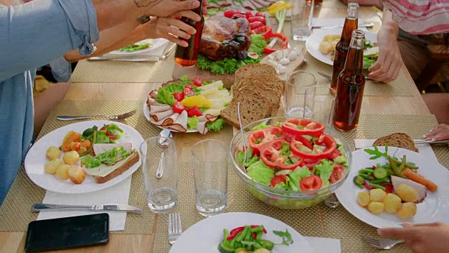 从上到下的移动镜头:大型家庭花园聚会庆典，人们吃，喝，传递菜肴。假日乐趣在一个阳光明媚的夏天。视频素材