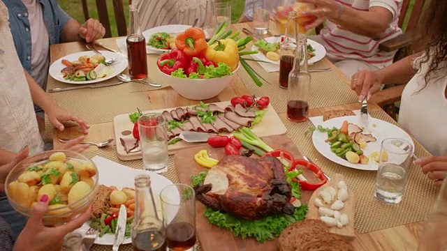 从上到下的移动镜头:大型家庭花园聚会庆典，人们吃，喝，传递菜肴。假日乐趣在一个阳光明媚的夏天。缓慢的运动。视频素材