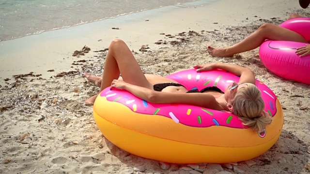 一个女人躺在沙滩上的充气床垫上。视频下载