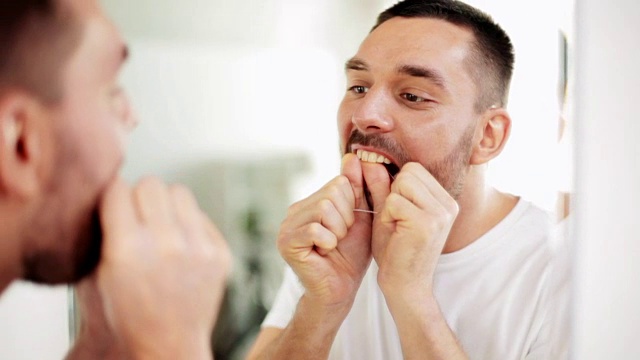一个男人在浴室用牙线清洁牙齿视频下载