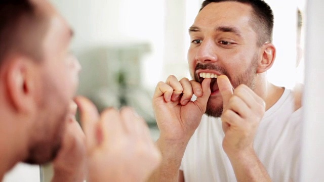 一个男人在浴室用牙线清洁牙齿视频素材
