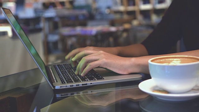 4k镜头镜头特写亚洲女商人的手与绿色屏幕笔记本电脑和喝咖啡拿铁艺术杯在咖啡咖啡馆，商业和生活方式的概念视频素材