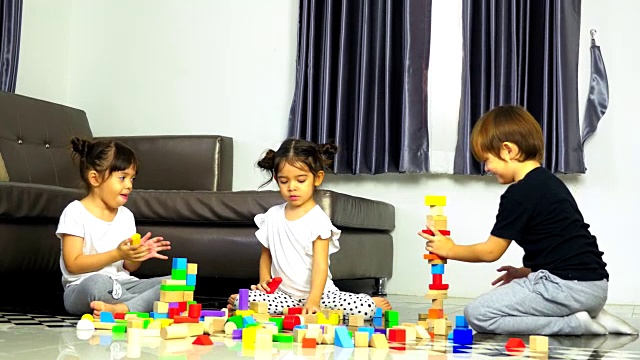 小男孩和小女孩在地板上玩木制玩具积木，在家里搭积木视频素材