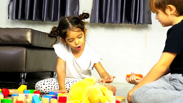 小男孩和小女孩在地板上玩木制玩具积木，在家里搭积木视频素材