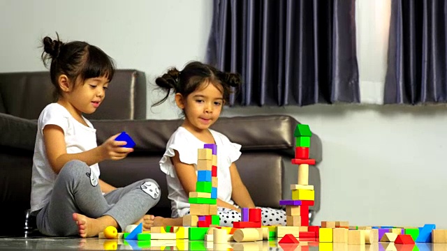 小女孩在地板上玩木制玩具积木，在家里搭高塔视频素材