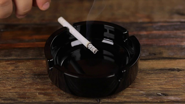 抽着烟，把烟灰摇到烟灰缸里。视频下载