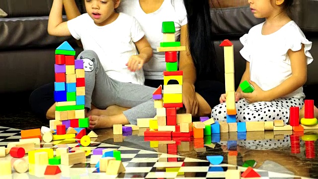 幸福的一家人一起在家里的客厅里度过时光，一家人在地板上玩积木木制玩具视频素材