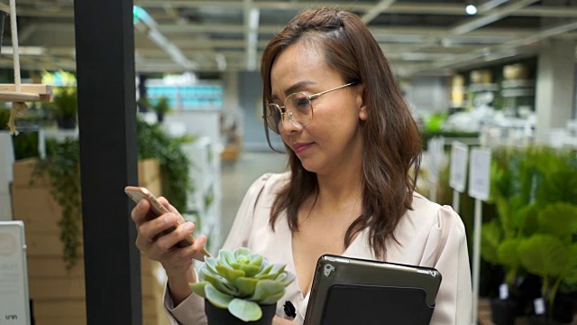 商业女性在花店检查库存的数字平板电脑和使用手机视频素材