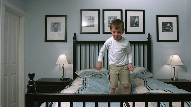 小男孩跳上床，慢动作视频素材