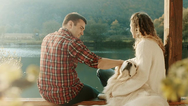 一对夫妇和一只狗坐在湖边视频素材