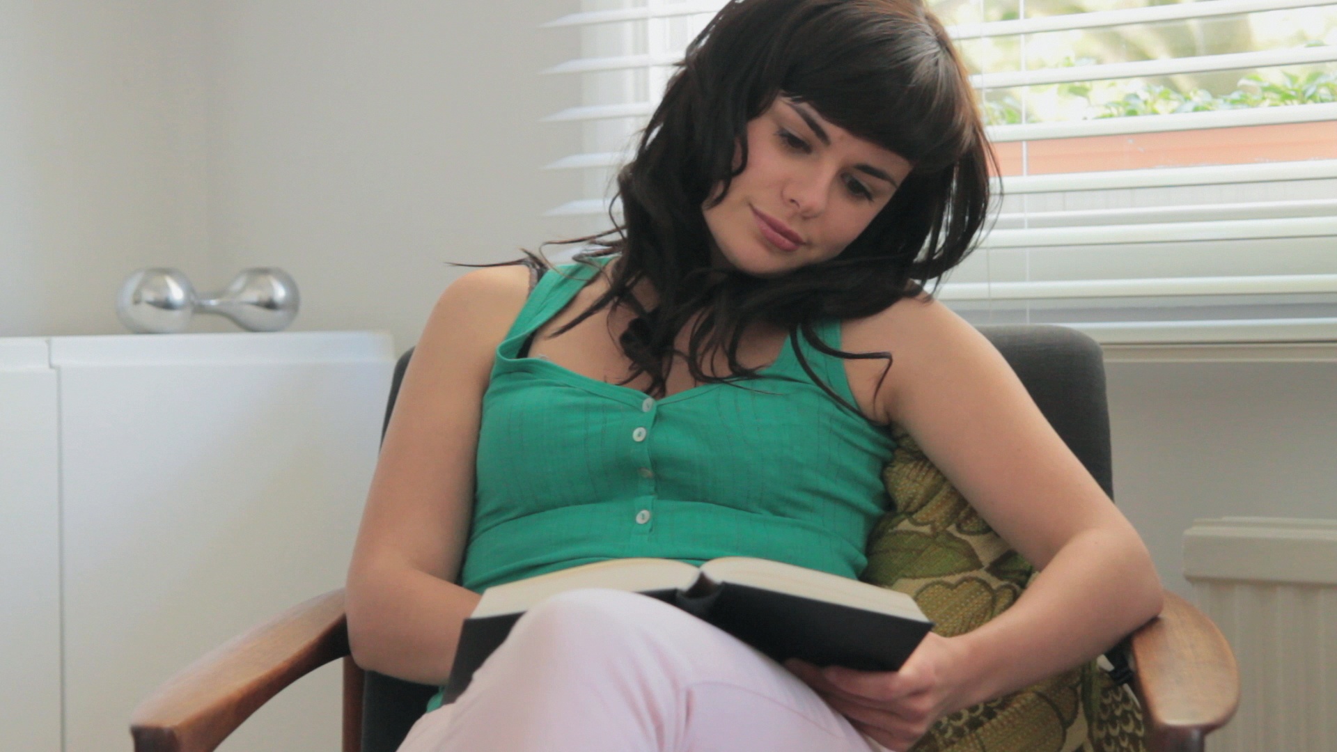英国伦敦，一个年轻女子坐在客厅的椅子上看书视频素材