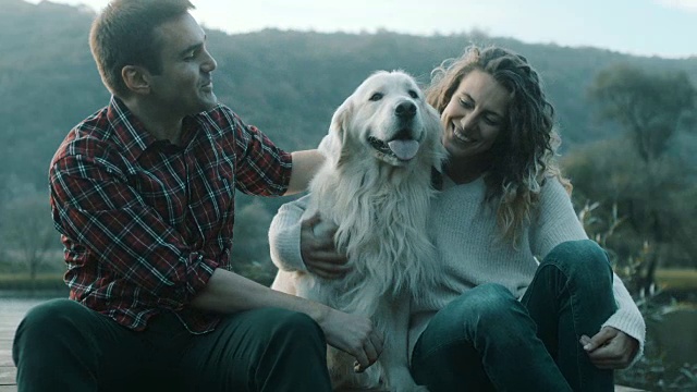 一对夫妇和一只狗在湖边拥抱视频素材