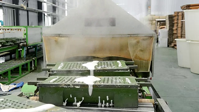 在橡胶枕厂，金属橡胶枕模具在传送带上用蒸汽加热出模视频素材