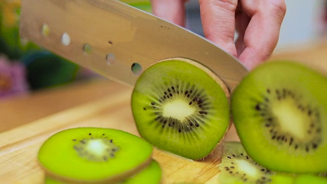 主妇们用刀在厨房餐桌的砧板上切着新鲜的猕猴桃视频素材