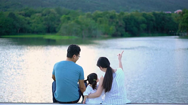 可爱的亚洲家庭放松与自然湖景背景和日落视频素材