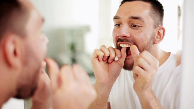 一个男人在浴室用牙线清洁牙齿视频素材