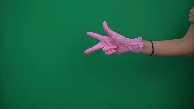 在绿色背景上戴上粉色手套视频素材