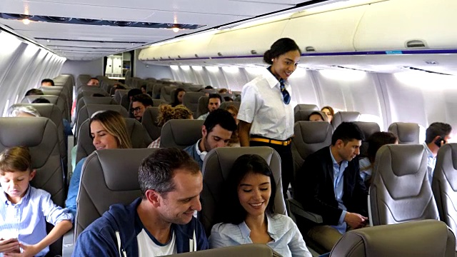 友好的黑人空姐关闭按钮，同时与女乘客交谈，以帮助她的东西视频素材