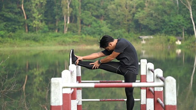 亚洲男子在湖边伸展双腿视频下载