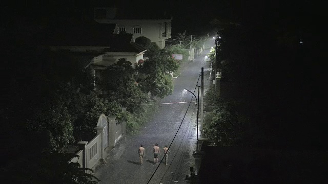 夜晚下雨的时候，在小街上行走的男人的剪影视频素材