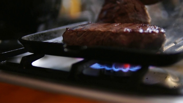 煤气炉和烤牛排在平底锅上。视频素材