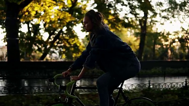 早上在公园或林荫大道上骑自行车的漂亮女人。一个年轻女子骑着一辆徒步旅行的自行车。关闭视图视频素材