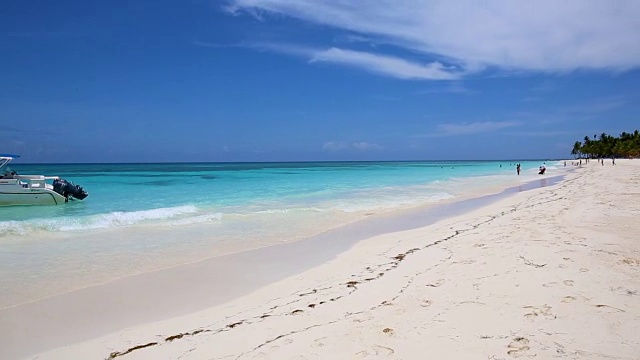 一艘船在一个热带岛屿的岸边，白色的沙子被蔚蓝的海水冲刷。加勒比群岛视频下载