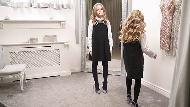 两个漂亮的女孩穿着成人高跟鞋在房间的镜子前走来走去。他们试图保持平衡视频素材