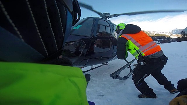 一架直升机降落，搭载滑雪者去山上滑雪。——慢动作视频下载