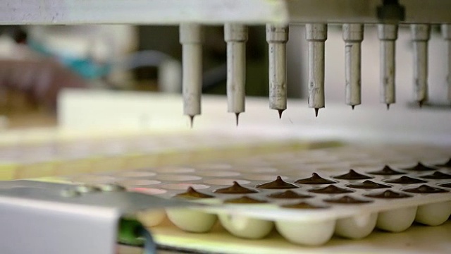糖果。生产巧克力的生产线。巧克力机-倒入模具视频素材