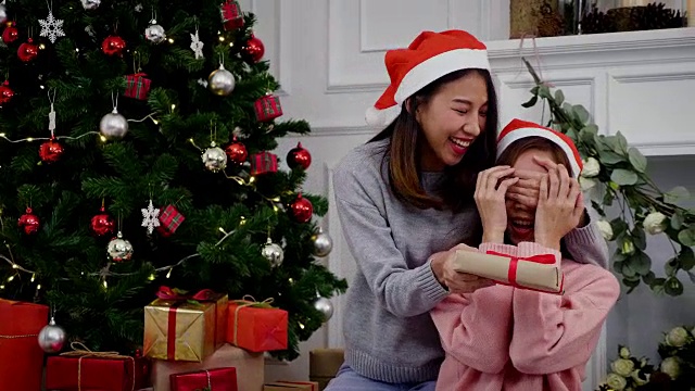 年轻的亚洲妇女在毛衣给圣诞礼物惊喜的朋友，圣诞节日的概念视频购买