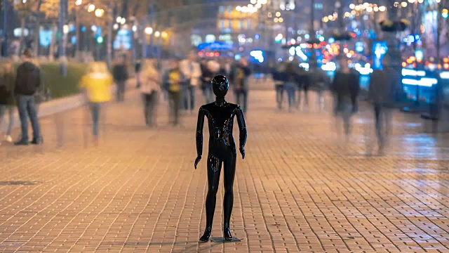 黑色的人体模型站在傍晚的街道上，人群川流不息视频素材