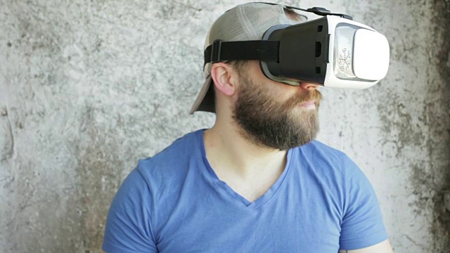 大胡子男子使用虚拟现实头盔显示器与耳机进行虚拟现实游戏。视频素材