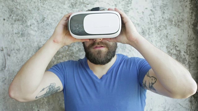 大胡子男子使用虚拟现实头盔显示器与耳机进行虚拟现实游戏。视频素材