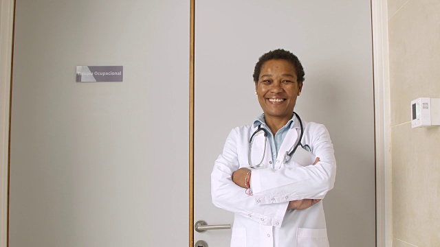 友好的非裔美国医生看着镜头微笑着交叉双臂视频素材