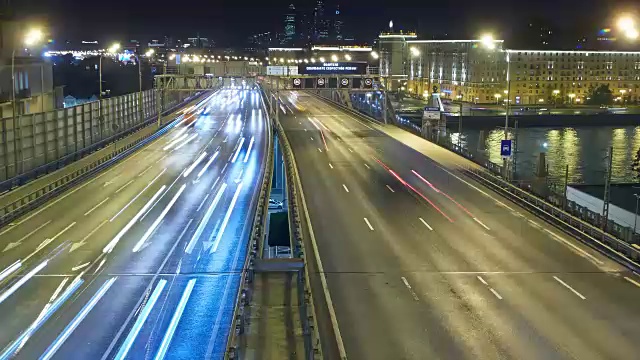 夜晚，河上桥上的车辆发出灯光。背景是摩天大楼。视频素材