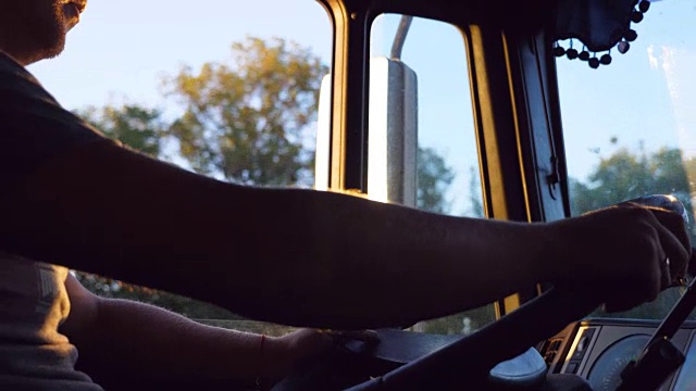 在一个炎热的夏天，一个面目全非的男人在乡村公路上驾驶着一辆卡车。在卡车驾驶室。侧视慢动作特写视频素材